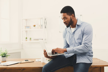 Wall Mural - Young black businessman working on laptop at office