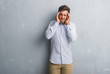 © Krakenimages.com - Handsome young business man over grey grunge wall wearing elegant shirt with hand on head for pain in head because stress. Suffering migraine.