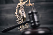 Judge Gavel and Lady Justice on a black wooden background.