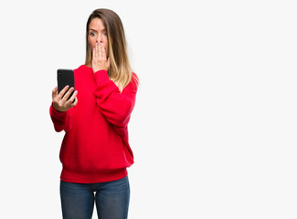 Sticker - Beautiful young woman using smartphone cover mouth with hand shocked with shame for mistake, expression of fear, scared in silence, secret concept