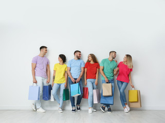 Poster - Group of young people with shopping bags near light wall