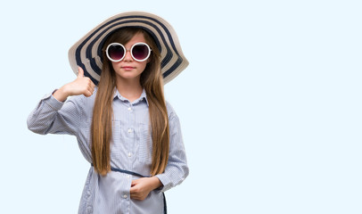 Sticker - Young blonde toddler wearing hat and sunglasses happy with big smile doing ok sign, thumb up with fingers, excellent sign