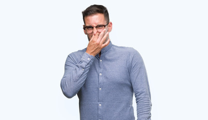 Wall Mural - Handsome young elegant man wearing glasses smelling something stinky and disgusting, intolerable smell, holding breath with fingers on nose. Bad smells concept.