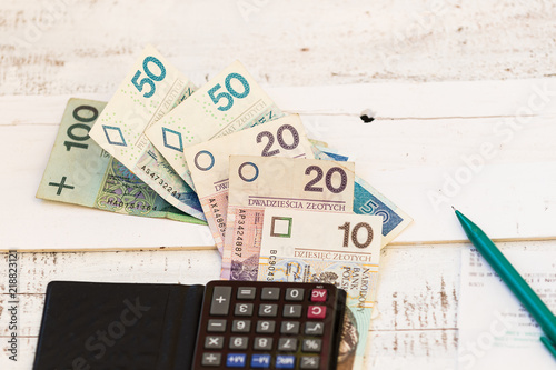 Fotomural Polish zloty banknotes with a black calculator and green pen on the white shabby