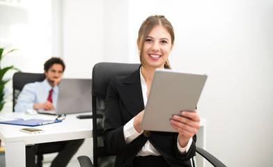 Wall Mural - Smiling woman using a tablet in her office