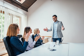 Wall Mural - Three business woman clapping to a male colleague after his presentation.