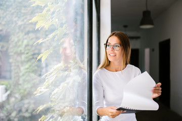 Wall Mural - Young businesswoman looking through window.