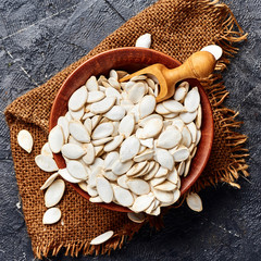 Wall Mural - Raw pumpkin seeds on black background. Top view.