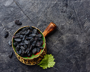 Wall Mural - Black raisins on gray background. Top view of dried grapes.