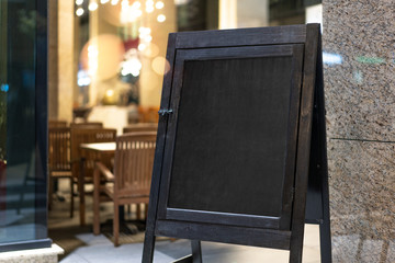 Wall Mural - Close up of black sandwich board next to restaurant.