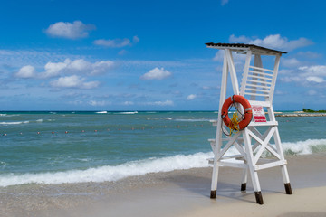 Wall Mural - Empty LifeGuard Chair with On Duty Hours sign and orange buoy, by the beach in Montego Bay, Jamaica.