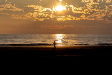 Formby beach in Merseyside at sunset, with the silhouette of a man walking on the shoreline