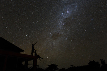 Couple on rooftop watching mliky way and catching stars in the night sky on Bali island