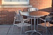 outdoor patio furniture aluminum chairs and table with reflection of brick wall