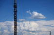 Metal construction of radio tower against the blue sky and white clouds