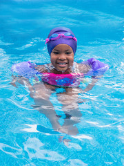 Wall Mural - A young African girl is enjoying swimming at summer time