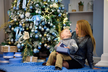 Happy family mother and baby little son playing home on Christmas holidays. New Year's holidays.