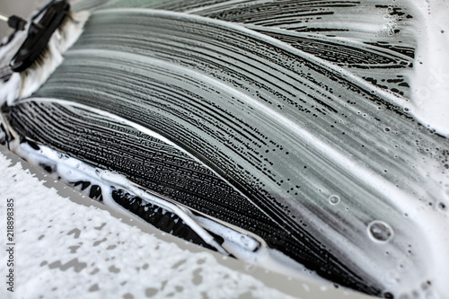 Fotografie, Obraz Brush leaving strokes in shampoo and foam on windshield of car washed at self service carwash