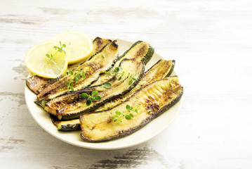 roasted zucchini slices on a plate, delicious vegetables, Mediterranean diet style cooking, rustic wooden background with copy space