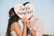 Young Wedding Couple Kissing And Holding Heart With Just Married Inscription