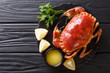 © FomaA - Delicious traditional boiled whole brown crab with sauce, lemon and parsley on a slate board close-up. Horizontal top view
