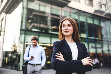 a portrait of a young businesswoman standing outdoors in front of a building.