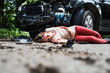 © Halfpoint - Young injured woman lying on the road after a car accident, unconscious.