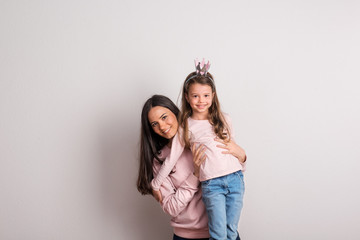 Wall Mural - A small girl with crown headband and her mother standing in a studio.