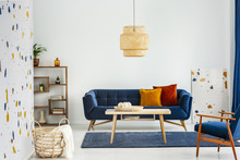 Lamp Above Wooden Table In Colorful Living Room Interior With Armchair And Blue Sofa. Real Photo