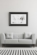© Photographee.eu - Black and white poster hanging on the wall above grey settee with pillows in real photo of living room interior with striped carpet