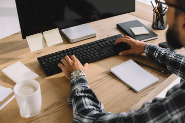 Wall Mural - cropped shot of bearded man in plaid shirt using computer at workplace