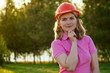 © yurakrasil - happy woman putting on a helmet hard hat in summer park, career guidance idea