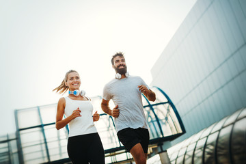 Young fitness couple running in urban area