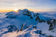 Stunning Sunset Or Sunrise In Winter Alpine Like Snow Landscape. Inversion, Sun Star Peaking Behind High Rocky And Icy Summit. Purple, Pink, Blue And Orange Colors. Ladovy Stit In Winter High Tatras.