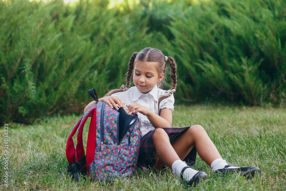little girl are sitting on the grass and reading book. Pupils of ...
