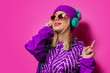 © Masson - Young girl with headphones in sports jacket on pink background.
