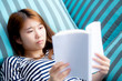 © NT_studio - Beautiful of portrait young asian woman relax lying reading book on sofa in bedroom at home, girl study literature, education and lifestyle concept.
