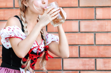 Beautiful woman drinks beer in Octoberfest dress.
