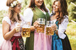 © karepa - Oktoberfest Freunde in Lederhosen und Dirndl trinken Bier an der Isar