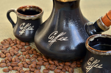 Coffee cezve with two cups and spilled coffee beans on sackcloth background