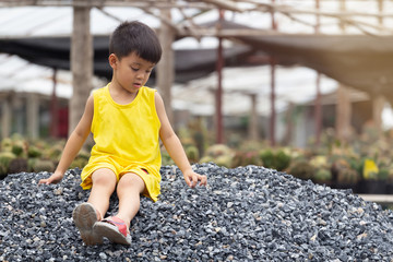 boy in yellow dress sitting and playing on pile of stones