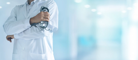 Male medicine doctor with stethoscope in hand standing confidently on hospital background