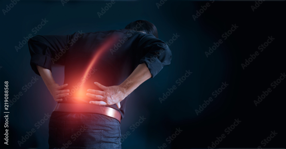 Man suffering from back pain cause of office syndrome, his hands touching on lower back. Medical and heathcare concept. - obrazy, fototapety, plakaty 