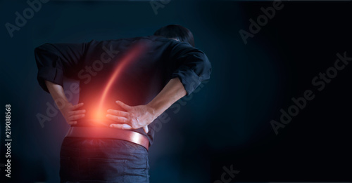 Cuadros en Lienzo Man suffering from back pain cause of office syndrome, his hands touching on lower back