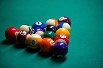 Wall Mural - Sport billiard balls set arranged in shape of triangle on green billiard table in pub. Players are ready for the first hit of the round to start the billiard game