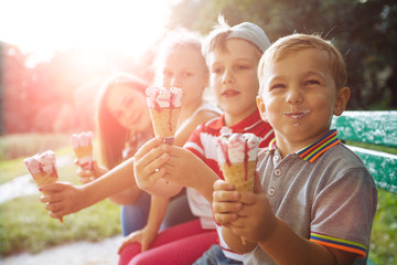 group of four happy children eating ice cream together outdoor. photo of happy blond girls with two 