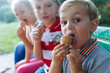 © Iryna - Team of three different age happy children eating ice-cream outdoors in park.