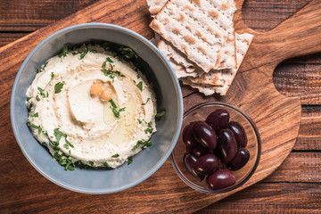 Wall Mural - top view of olives, pita bread and hummus with parsley and chickpeas in bowl on cutting  board wooden surface