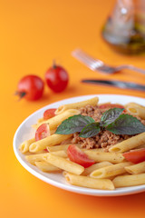 Wall Mural - Pasta Fettuccine Bolognese with tomato sauce and basil in white dish on the orange background.