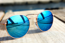 Glasses With Blue Glasses On The Sun Lie On A Wooden Floor Rest Trip Reflected In A Glass...
